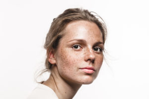 Young beautiful freckles woman face portrait with healthy skin