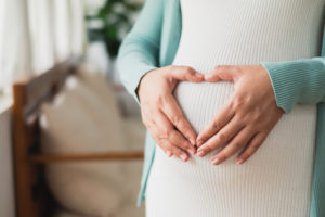 close up of pregnant woman's belly with her hands on her belly