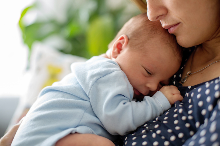 Young mother, holding tenderly her newborn baby boy, close portrait