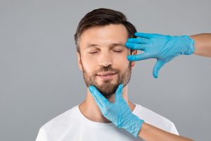 doctors hands in gloves inspecting mans face
