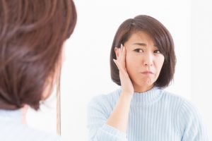 woman checking her skin in a mirror