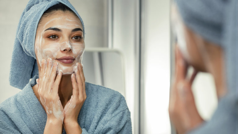 woman wearing a face mask for skin treatment looking in mirror