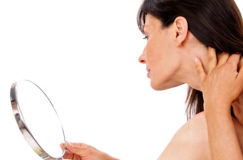 woman inspecting her jawline in a mirror